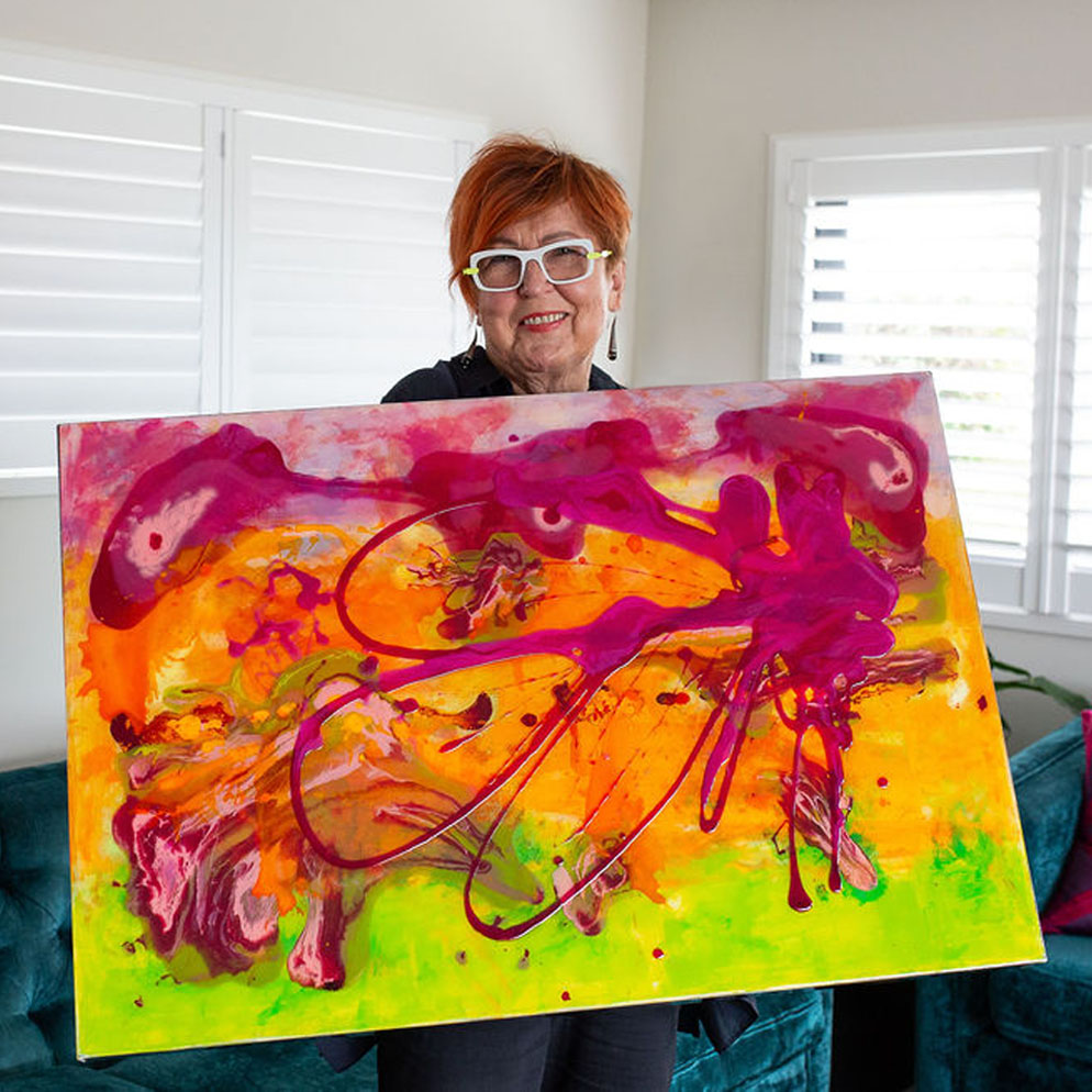 Sue Mac Dougall holding Aetheria, an original abstract floral painting with resin and gold-mirrored frame edges